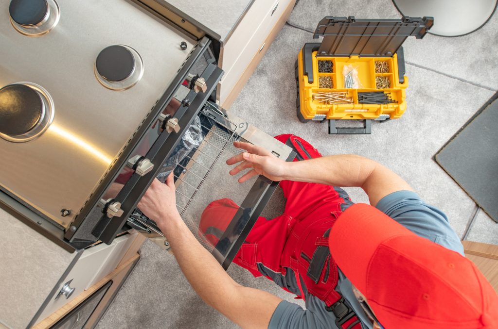 Service technician repairing a home appliance with professional tools. Represents Appliance Man appliance repair services including refrigerators, freezers, dishwashers, washing machines, dryers, microwaves, ovens, stoves, and cooktops.